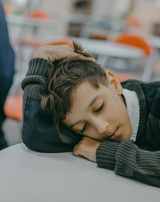 Child resting head on desk at home