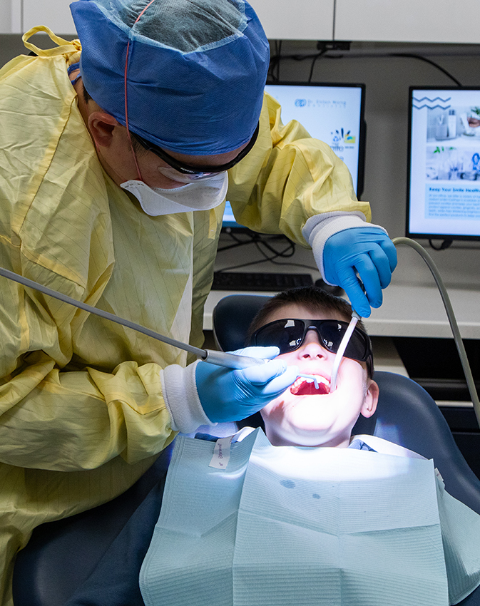 Dentist wearing protective gear treating patient