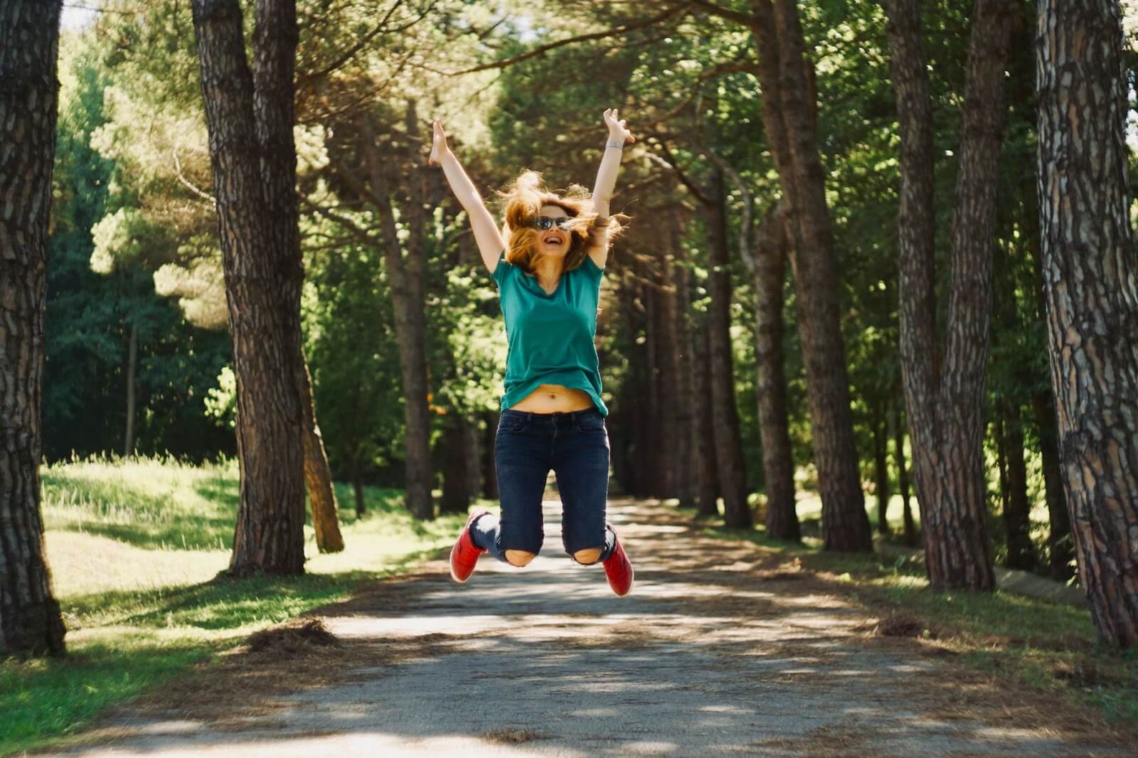 a woman outside jumping up in the air excitedly